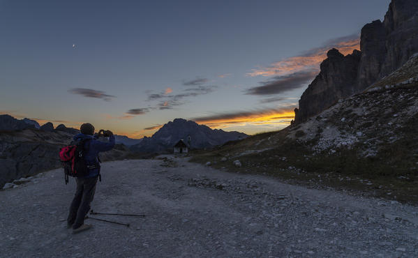 Tre Cime di Lavaredo, Three peaks of lavaredo, Drei Zinnen, Dolomites, Veneto, South Tyrol, Italy. Hiker photographs sunset at Tre Cime di Lavaredo