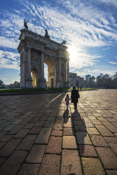 Milan, Lombardy, Italy. A woman walk with her child at the Arch of the peace square.