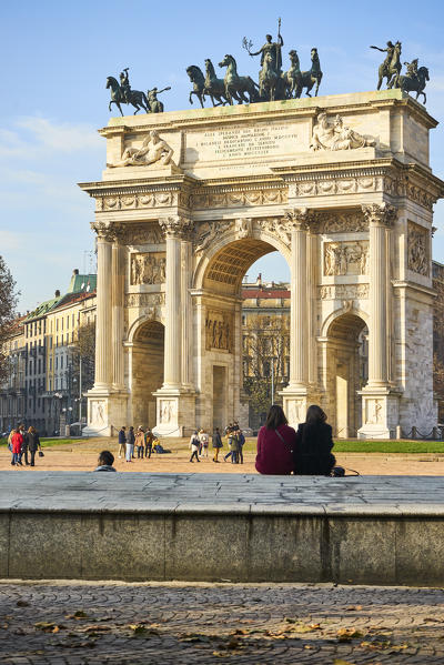 Milan, Lombardy, Italy. Girls are sitting in front the Arch of the Peace.
