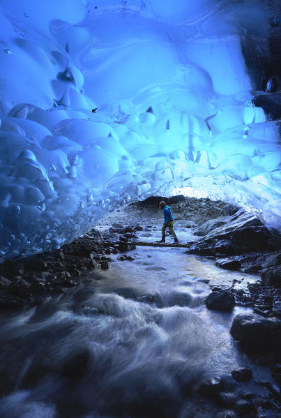 Skaftafell national park, Iceland, Europe. Man in a blue crystal ice cave under the Vatnajokull glacier in winter.