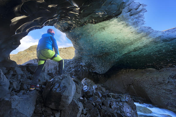Skaftafell national park, Iceland, Europe. Man admire the blue crystal ice cave under the Vatnajokull glacier in winter.