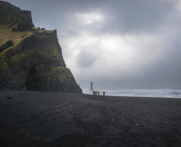 Beach of Reynisfjara, Vik, Sudurland, Iceland, Europe. A group of photographers walks on the black beach.