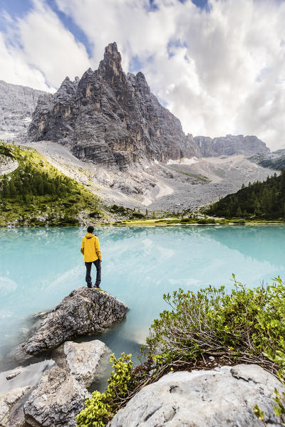 Italy,Veneto,province of Belluno,hiker admires the turquoise water of Lake Sorapis,dominated by the Sorapis Group with Dito di Dio peak (God's finger)(MR)