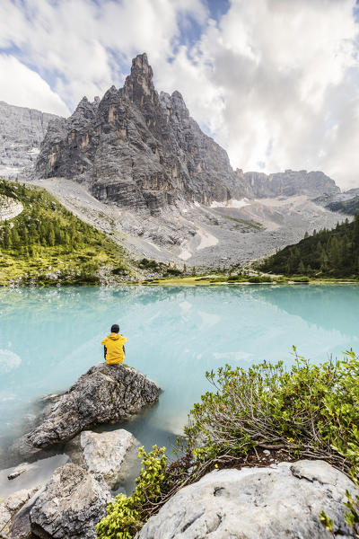 Italy,Veneto,province of Belluno,a hiker enjoys the peaceful at the Sorapis lake,dominated by the Sorapis Group with Dito di Dio peak (God's finger)(MR)