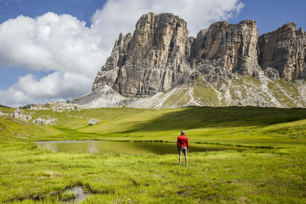 Italy, Veneto, province of Belluno, hiker admires the Lastoni di Formin from Baste lake (MR)