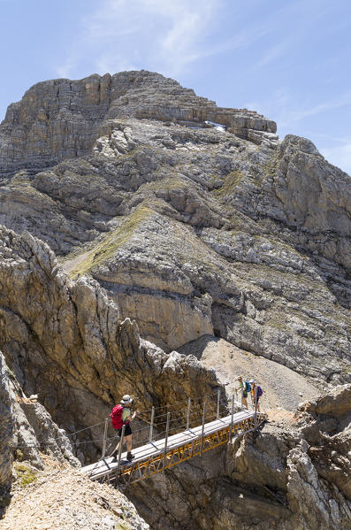 Italy,Veneto,Belluno district,Cortina d'Ampezzo,Hiker crosses a short suspended bridge on the trail to Mount Croda del Vallon Bianco
