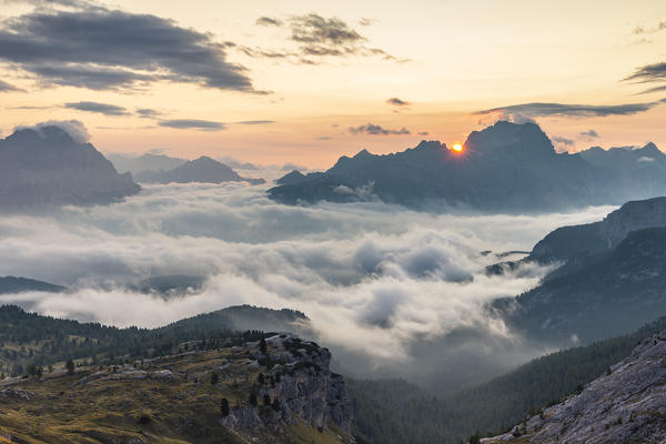 The sun rises in Cortina d'Ampezzo hidden by the morning fog, Belluno district, Veneto, Italy