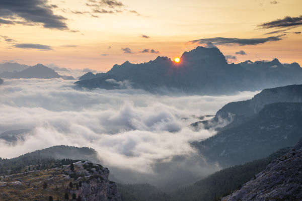 The sun rises in Cortina d'Ampezzo hidden by the morning fog, Belluno district, Veneto, Italy