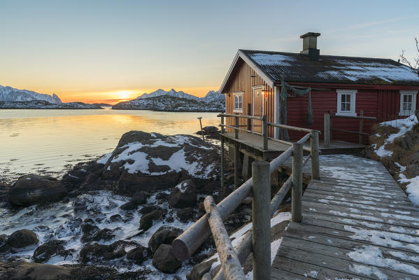 Typical fishermen red house on the sea at dawn in winter. Svolvaer, Nordland county, Northern Norway region, Norway.