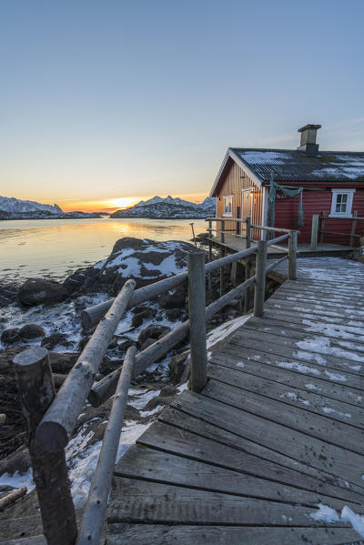 Typical fishermen red house on the sea at dawn in winter. Svolvaer, Nordland county, Northern Norway region, Norway.