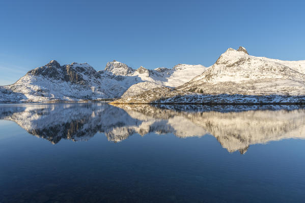 Snowcapped mountains reflect on Husvagen fjord in winter. Svolvaer, Nordland county, Northern Norway region, Norway.