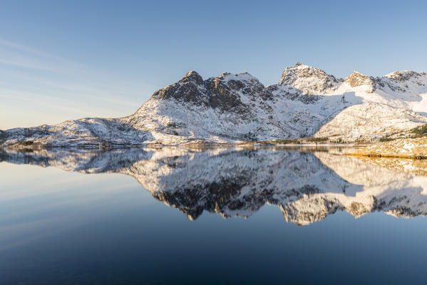 Snowcapped mountains reflect on Husvagen fjord in winter. Svolvaer, Nordland county, Northern Norway region, Norway.