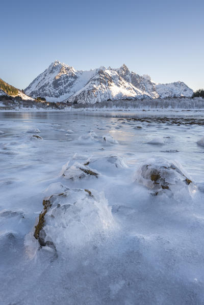 Frozen bay in Austnesfjord with snowcapped mountains in the background. Vestpollen, Nordland county, Northern Norway region, Norway.
