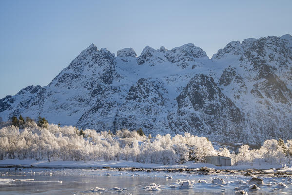 Frozen bay in Austnesfjord with snowcapped mountains in the background. Vestpollen, Nordland county, Northern Norway region, Norway.