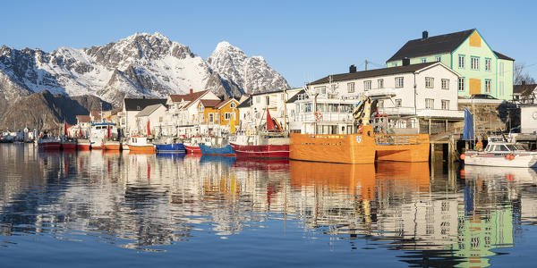 Fishing boats in the harbour, with snowcapped mountains in the background. Henningsvaer, Nordland county, Northern Norway region, Norway.