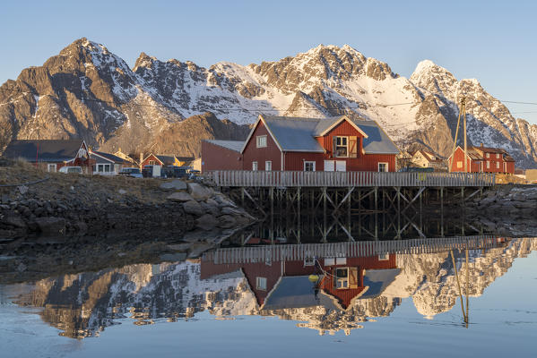 Reflection of typical fishing houses with mountains in the background in wnter. Henningsvaer, Nordland county, Northern Norway region, Norway.