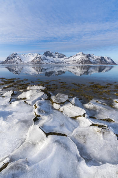 Ice on the beach with Limstrandtinden snowcapped group in the background. Vestvagoy municipality, Lofoten district, Nordland county, Norway.
