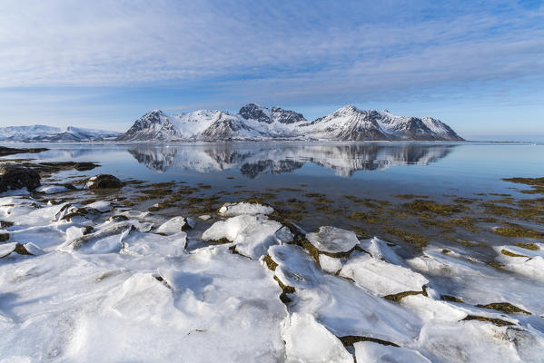 Ice on the beach with Limstrandtinden snowcapped group in the background. Vestvagoy municipality, Lofoten district, Nordland county, Norway.