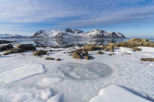 Ice on the beach with Limstrandtinden snowcapped group in the background. Vestvagoy municipality, Lofoten district, Nordland county, Norway.
