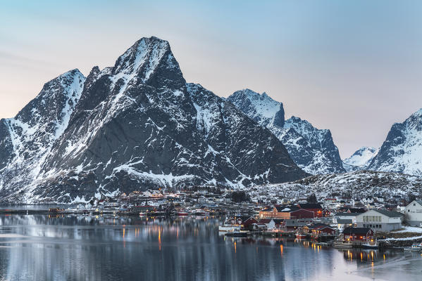 Reine Bay at sunset in winter, with Olstinden peak in the background. Reine, Nordland county, Northern Norway, Norway.