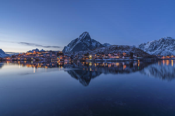 Reine Bay at dusk in winter, with Olstinden peak in the background. Reine, Nordland county, Northern Norway, Norway.