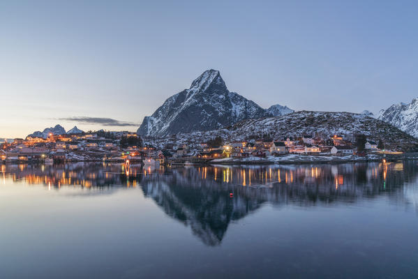Reine Bay at dusk in winter, with Olstinden peak in the background. Reine, Nordland county, Northern Norway, Norway.