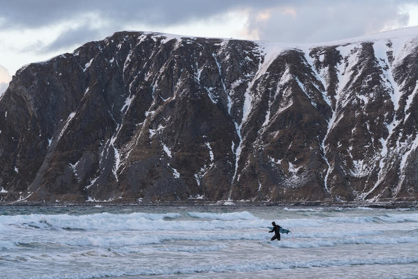 Man surfboarding in the sea in winter. Skagsanden beach, Flakstad, Nordland county, Northern Norway, Norway.