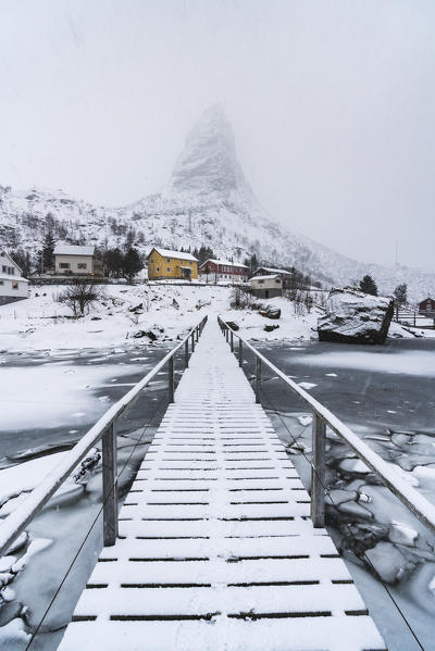 Bridge on the fjord with Hammarskaftet peak in the background covered in mist. Reine, Nordland county, Northern Norway, Norway.