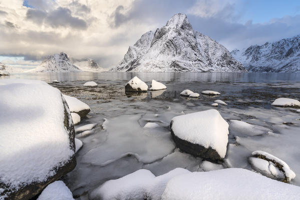 Olstinden peak in winter, with ice and snow on the rocky beach in the foreground. Reine, Nordland county, Northern Norway region, Norway.