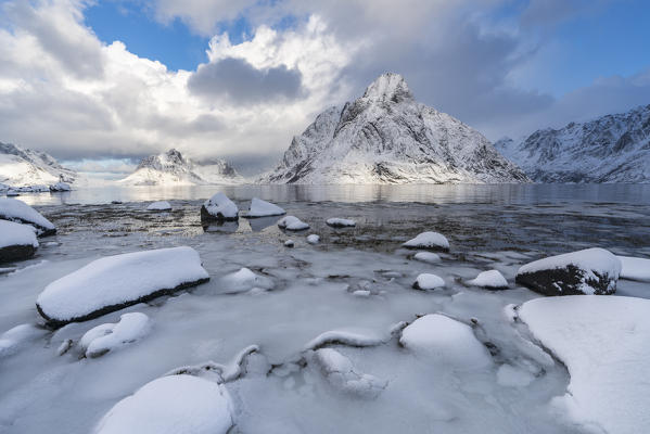 Olstinden peak in winter, with ice and snow on the rocky beach in the foreground. Reine, Nordland county, Northern Norway region, Norway.