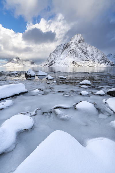 Olstinden peak in winter, with ice and snow on the rocky beach in the foreground. Reine, Nordland county, Northern Norway region, Norway.