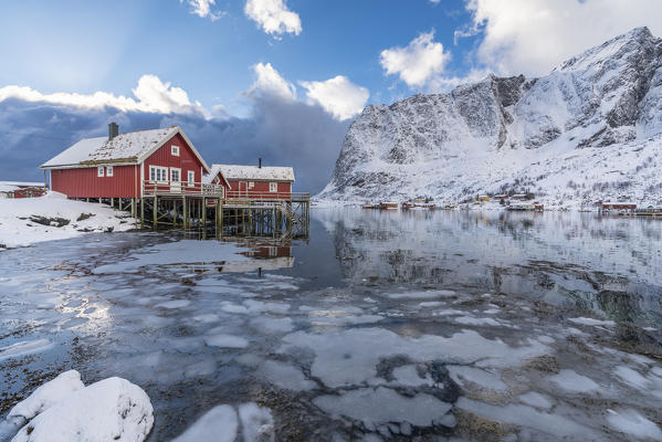 Traditional 'rorbu' houses with Renebringen peak in the background in winter. Reine, Lofoten district, Nordland county, Northern Norway, Norway.