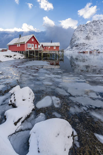 Traditional 'rorbu' houses with Renebringen peak in the background in winter. Reine, Lofoten district, Nordland county, Northern Norway, Norway.