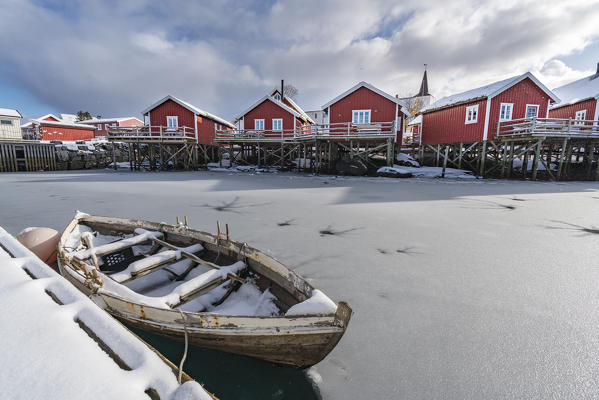 Traditional 'rorbu' houses and boat in the foreground, in winter. Reine, Lofoten district, Nordland county, Northern Norway, Norway.