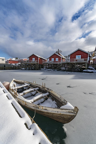 Traditional 'rorbu' houses and boat in the foreground, in winter. Reine, Lofoten district, Nordland county, Northern Norway, Norway.