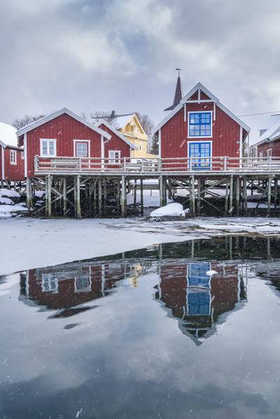 Traditional 'rorbu' houses reflected on the frozen fjord. Reine, Lofoten district, Nordland county, Northern Norway, Norway.