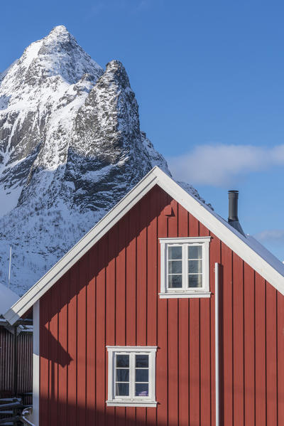 Traditional 'rorbu' house and Navaren peak in the background, in winter. Reine, Lofoten district, Nordland county, Northern Norway, Norway.