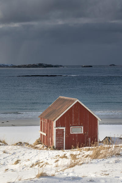 Red cabin in the snow on Ramberg beach. Flakstad municipality, Nordland county, Northern Norway, Norway.