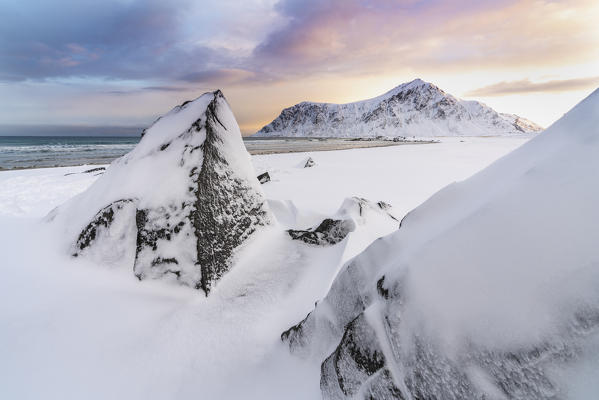 Skagsanden beach at dawn in winter, with rocks in the foreground. Flakstad, Nordland county, Northern Norway, Norway.