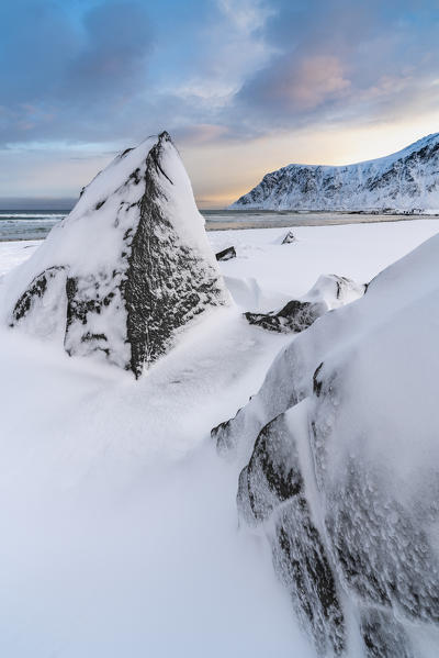 Skagsanden beach at dawn in winter, with rocks in the foreground. Flakstad, Nordland county, Northern Norway, Norway.