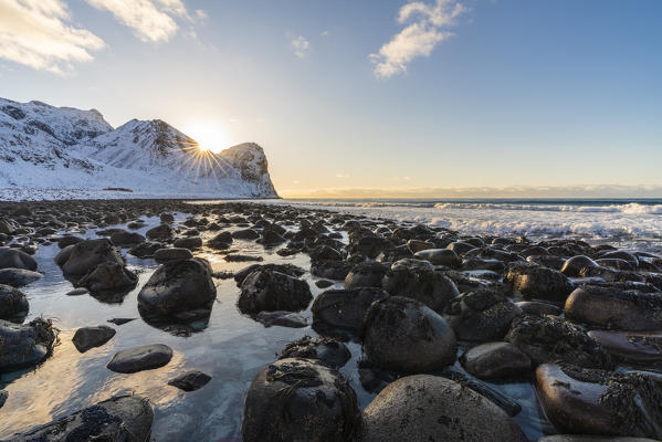 The sun is setting behind Helligberget peak at Unstad Beach. Vestvagoy municipality, Nordland county, Northern Norway, Norway.
