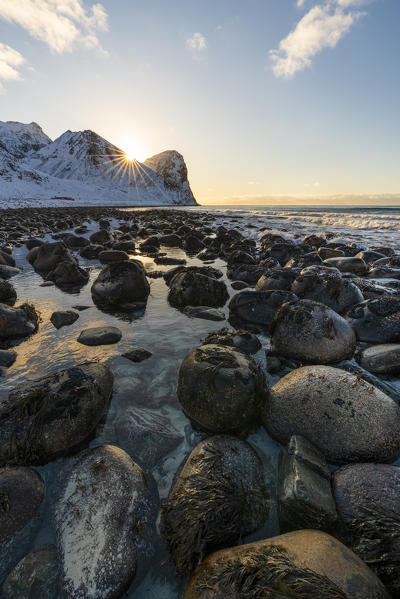 The sun is setting behind Helligberget peak at Unstad Beach. Vestvagoy municipality, Nordland county, Northern Norway, Norway.