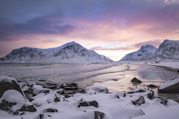Skagsanden beach at dawn in winter, with rocks in the foreground. Flakstad, Nordland county, Northern Norway, Norway.