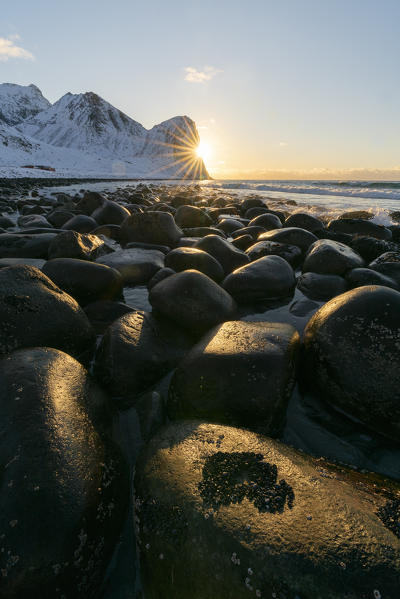 The sun is setting behind Helligberget peak at Unstad Beach. Vestvagoy municipality, Nordland county, Northern Norway, Norway.
