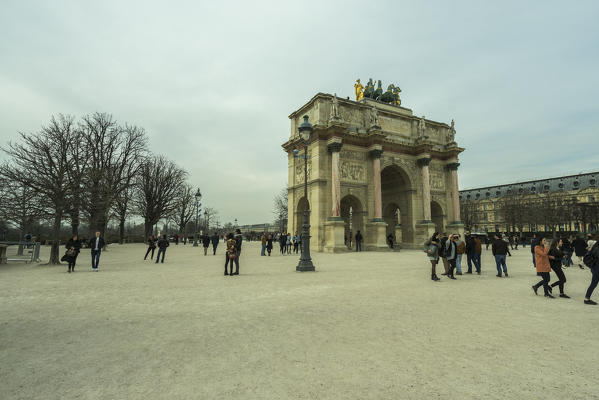 Tourists walk near The Triumphal Arch (de Triomphe du Carrousel) in front of the Louvre museum. Paris, France