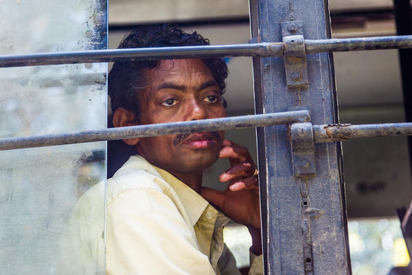 India, Delhi, Man looking through bus window