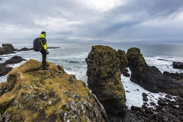 A man admires the ocean and its rocks near Arnarstapi, Snaefellsnes peninsula, Western Iceland, Europe.