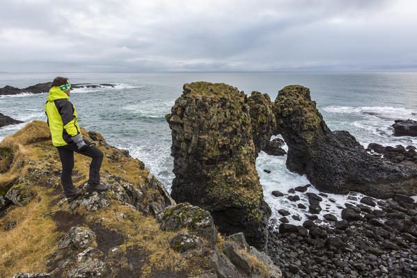 A man admires the ocean and its rocks near Arnarstapi, Snaefellsnes peninsula, Western Iceland, Europe.