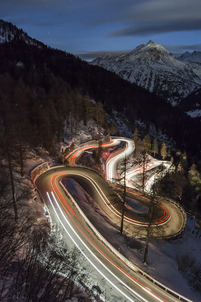 Car lights on the curvy Maloja Pass road at night. Maloja Pass, Engadin, Graubunden, Switzerland.