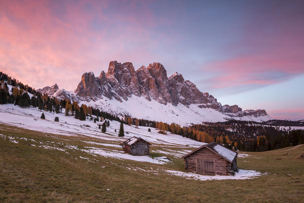 Sunrise with two wooden lodges and Odle Dolomites. Malga Gampen, Funes, Bolzano, Trentino Alto Adige - Sudtirol, Italy, Europe.